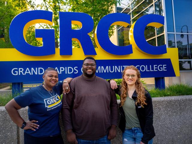 GRCC students standing in front of the GRCC campus sign