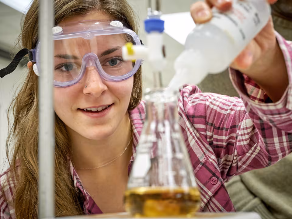 GRCC student adding solution to a beaker in a chemistry class