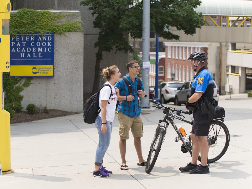 Campus police on bicycle talking to students.