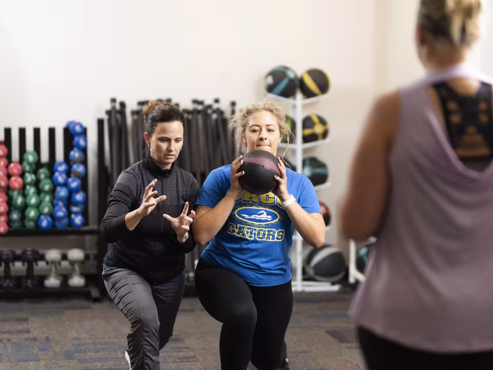 Professor shows student how to hold weighted ball.