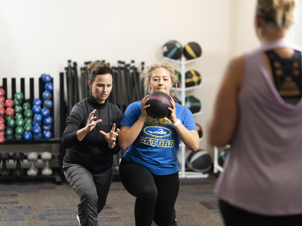 Professor shows student how to hold weighted ball.