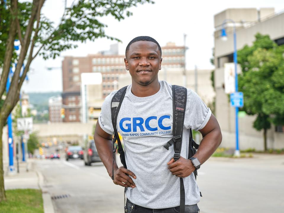 A smiling student wearing a GRCC t-shirt stand at the to of Lyon street hill