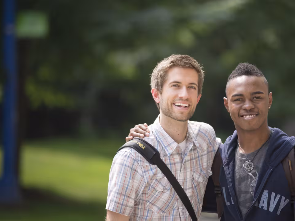 Two students smiling outside Sneden Hall