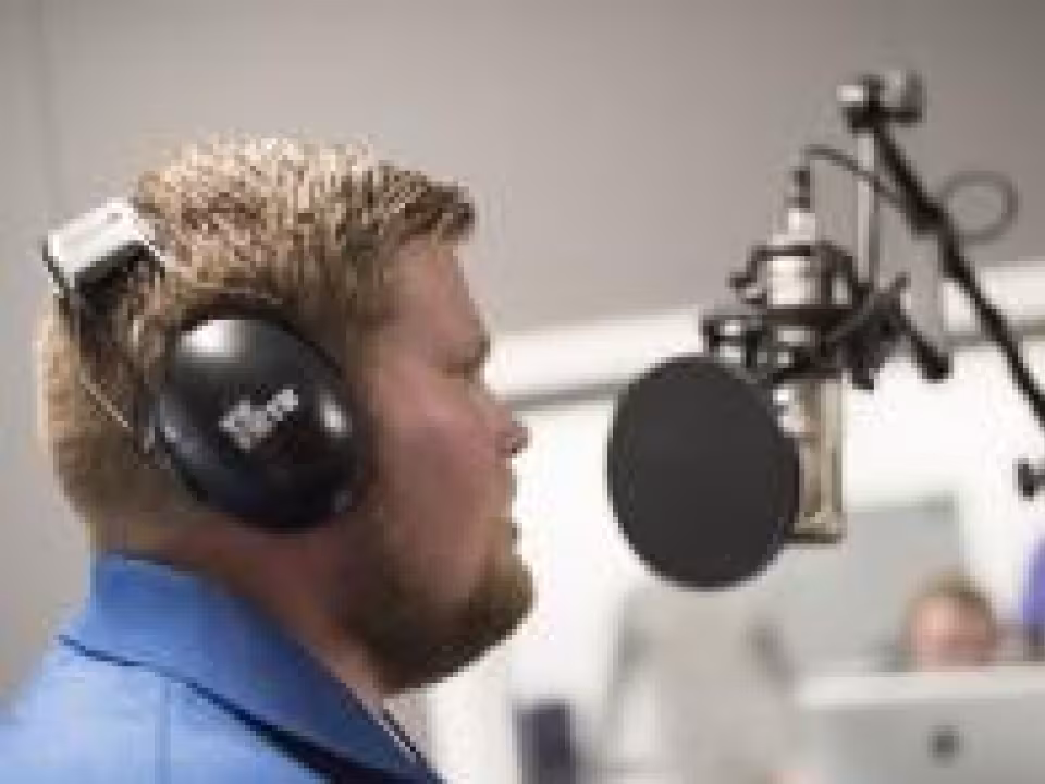 GRCC student using a microphone in the recording studeo.