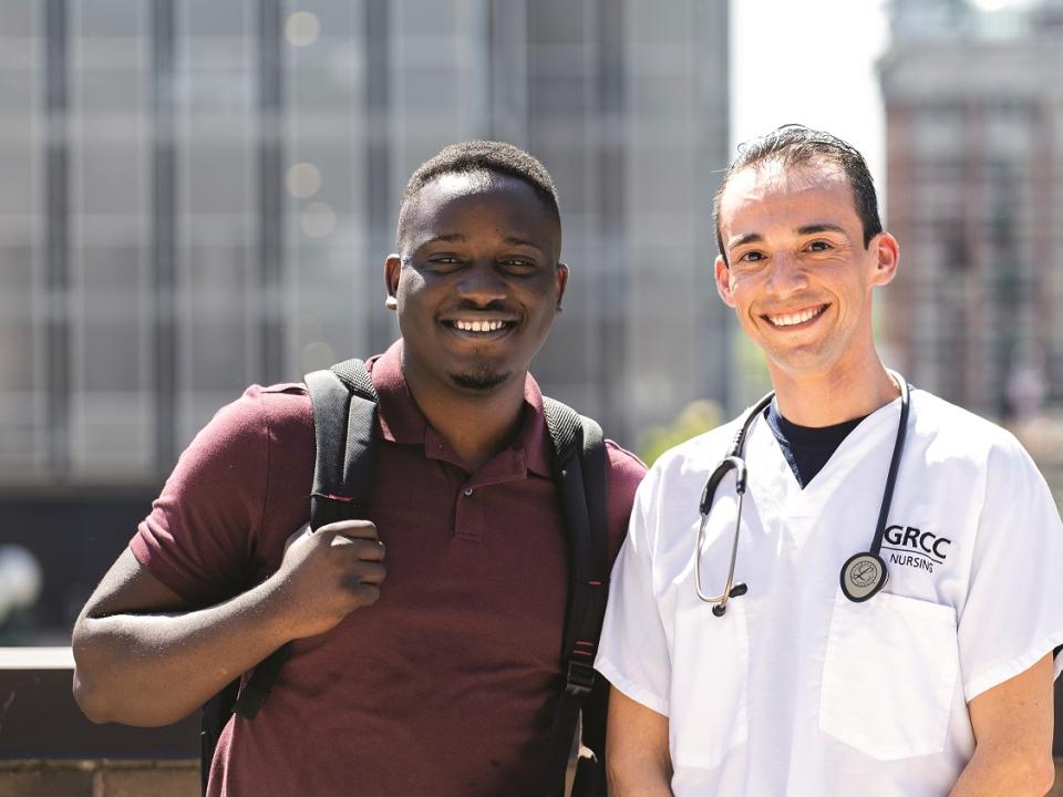 Two students standing outside with downtown view as the backdrop.