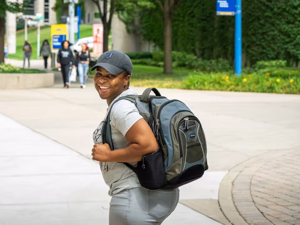 Student walking on the plaza with a backpack