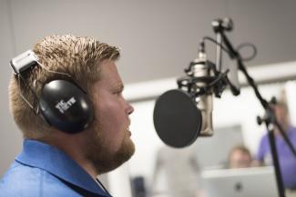 GRCC student using a microphone in the recording studeo.