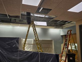 A ladder extends above the drop ceiling, where duct work is visible.