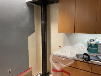 A pipe runs next to a cabinet.