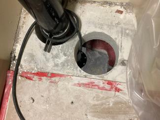 A pipe runs through a panel next to an open hole.