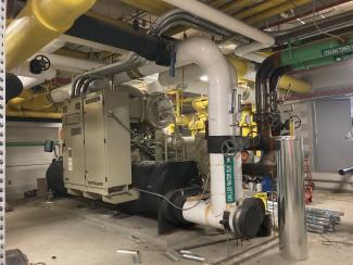 A large machine connects to white and black pipes.