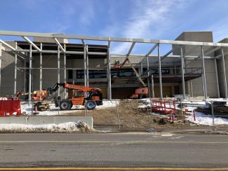 A large, seel beam structure outside a concrete building exterior