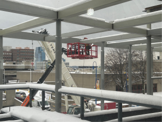 A person in a lift works on steel beams