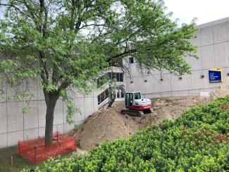 Excavator moving dirt near entrance.