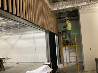 A construction worker is hanging the wood on the feature wall