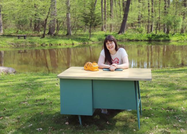Abby Haywood sitting at a desk near a pond. 