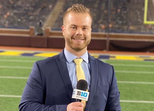 Amer posing with a microphone on the field at U of M.