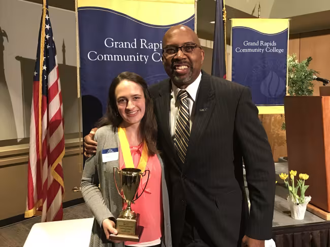 Heather Stadt holds the Arthur Andrews Award. President Pink stands next to her with his arm on her shoulder.