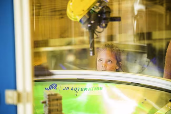 Future engineer watching a robotic arm in action.