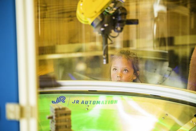 Future engineer watching a robotic arm in action.