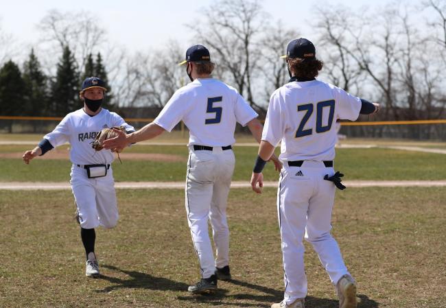 GRCC baseball players celebrating after scoring a run.