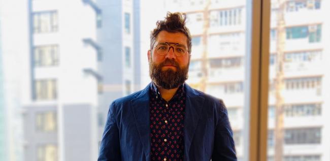 Portrait of Ben Gerlofs with buildings in the background.
