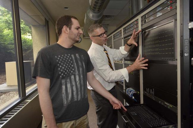 GRCC Computer Information Systems Department Head Drew Rozems shows a student parts of a main frame computer system.