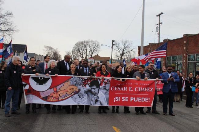 Scene from the 2019 Chavez march, with marchers walking behind a large banner.