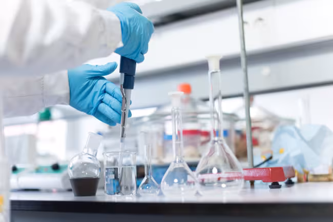 A person uses chemistry equipment to work with liquid in a beaker.