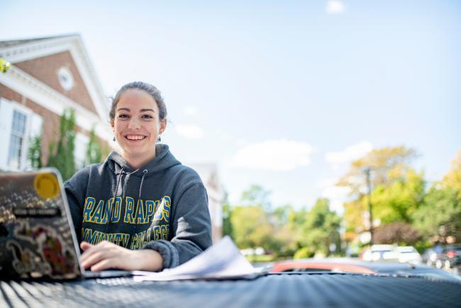 GRCC student sitting on the DeVos Campus with her laptop.