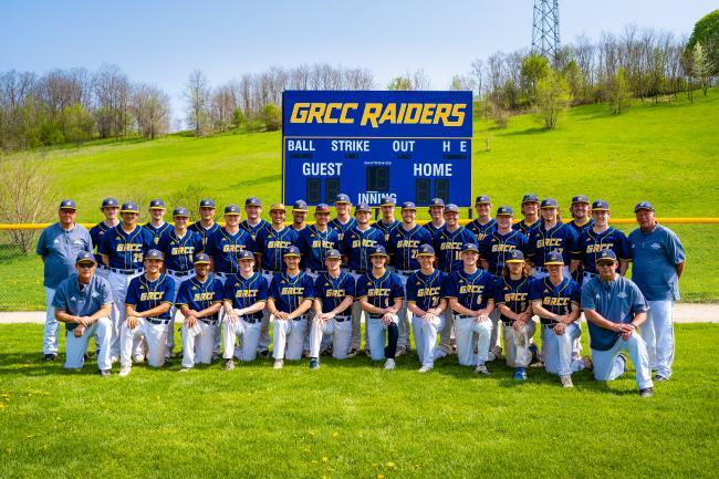 GRCC baseball team members pose in front a scoreboard.