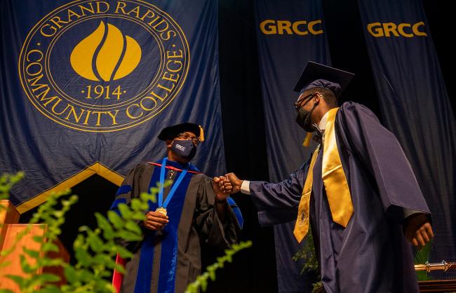 GRCC President Bill Pink fist-bumps a graduate.