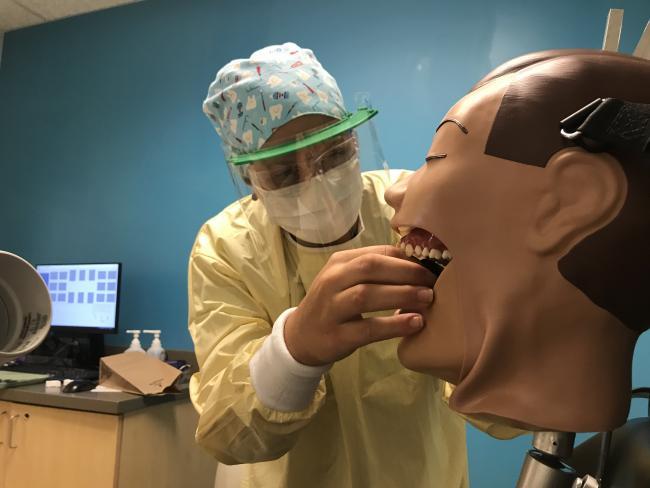 Dental student Sydney Heyboer learning how to take x-rays, wearing her PPE.