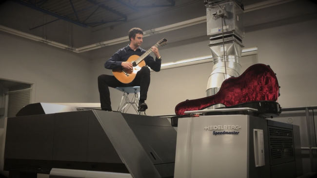 GRCC guitar instructor Jonathan Marshall performing atop a printing machine.