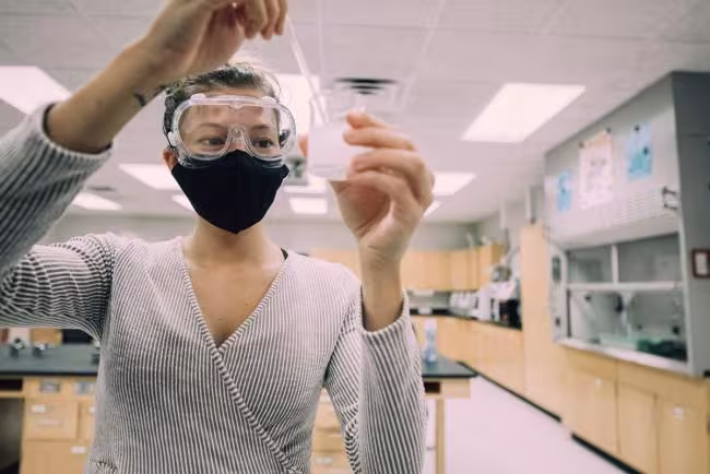 Chemistry student stirring contents of a beaker 