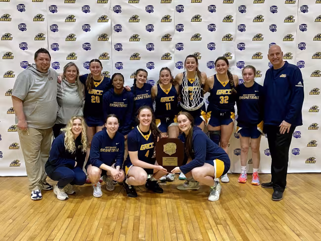 Team photo of the basketball players with their trophy.
