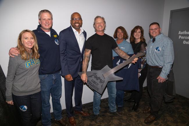 Metallica guitarist James Hetfield holds a guitar made by GRCC welding professors surrounded by GRCC President Pink and staff.                            ors