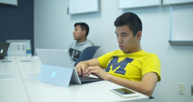 GRCC student wearing a University of Michigan shirt while working on his laptop
