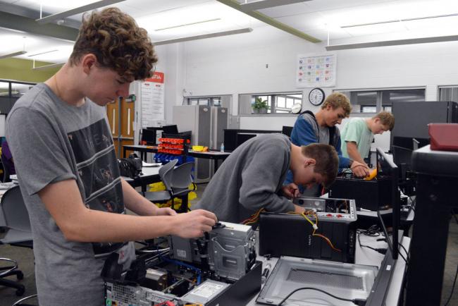 Launch U IT Program students Cole Lake, Aidan Byrne and others work on devices at the Tech Center.