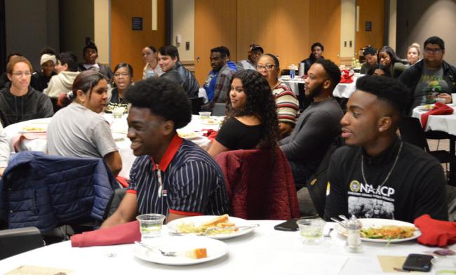 Students sitting a table reacting to a speaker.