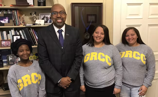 GRCC President Pill Pink posing in his office with the valedictorian from Central Innovation High and the valedictorian and salutatorian from Ottawa Hills High.