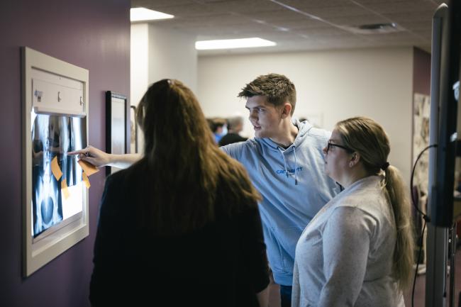 Three people examine an X-ray.