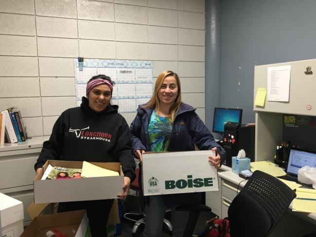 Two TRIO students hold up boxes of school supplies.