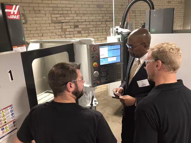 GRCC President Bill Pink with two students looking at machinery at the AMP Lab