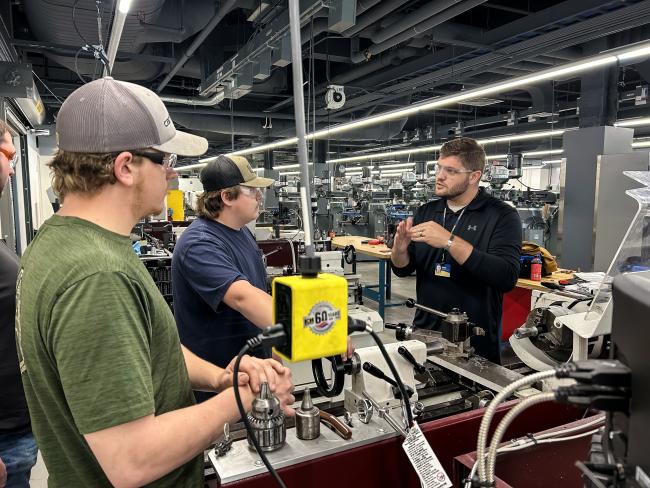 Jake Nichols speaks with two students in a machine lab.