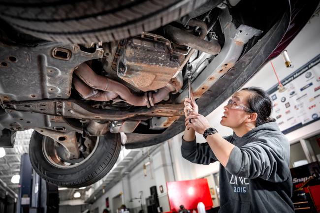 Student working under a car in a GRCC Automotive Tech class.