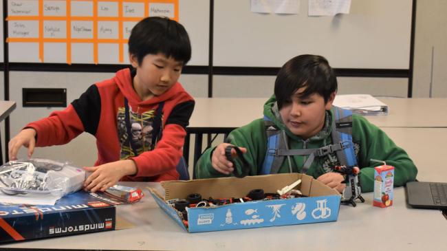 Kelloggsville Middle School students Cody Liang and Eman Marasigan look through a box of parts for their robot.