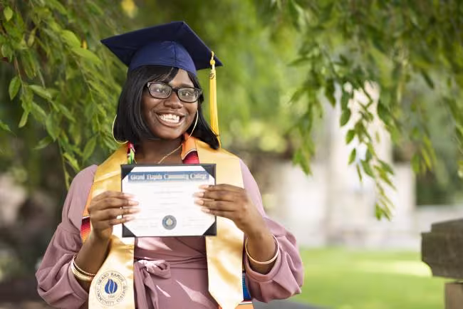Graduate Keylaih Brown wearing her cap and tassel with her GRCC diploma.