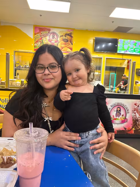 GRCC student Leah Santiago holds her young daughter, Xylia, in her arms for a photo.