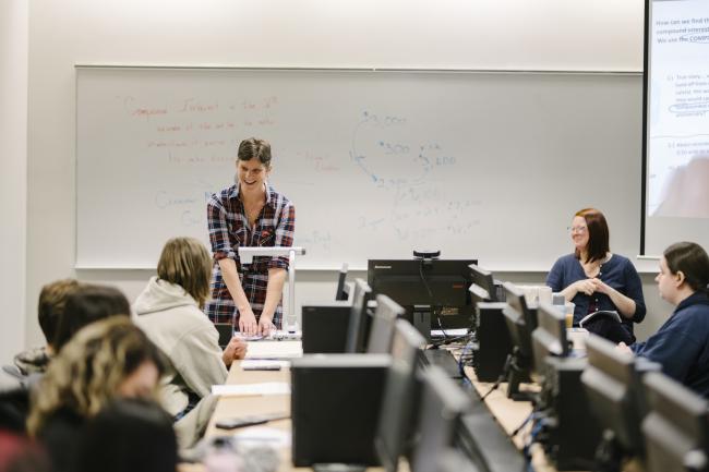 A math professor talks with students in the classroom.